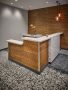 small reception desk with marble and chestnut-colored wood siding, patterned black and white carpet, and an accent wall with a triangular pattern