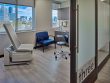 view into the entry door of a medical exam room with blue seating and windows with a view of the Atlanta city skyline