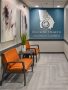 Beltline Health hallway with orange couches, abstract wall art, a decorative plant and blue logo wall